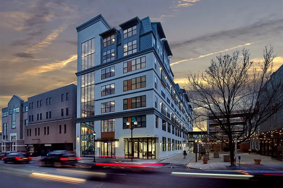 Cars speeding by an apartment building with a lot of windows