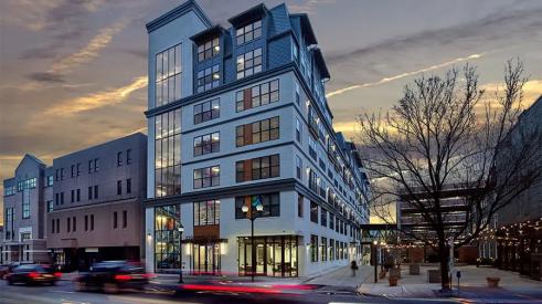 Cars speeding by an apartment building with a lot of windows