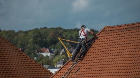 Roofer with harness on rooftop